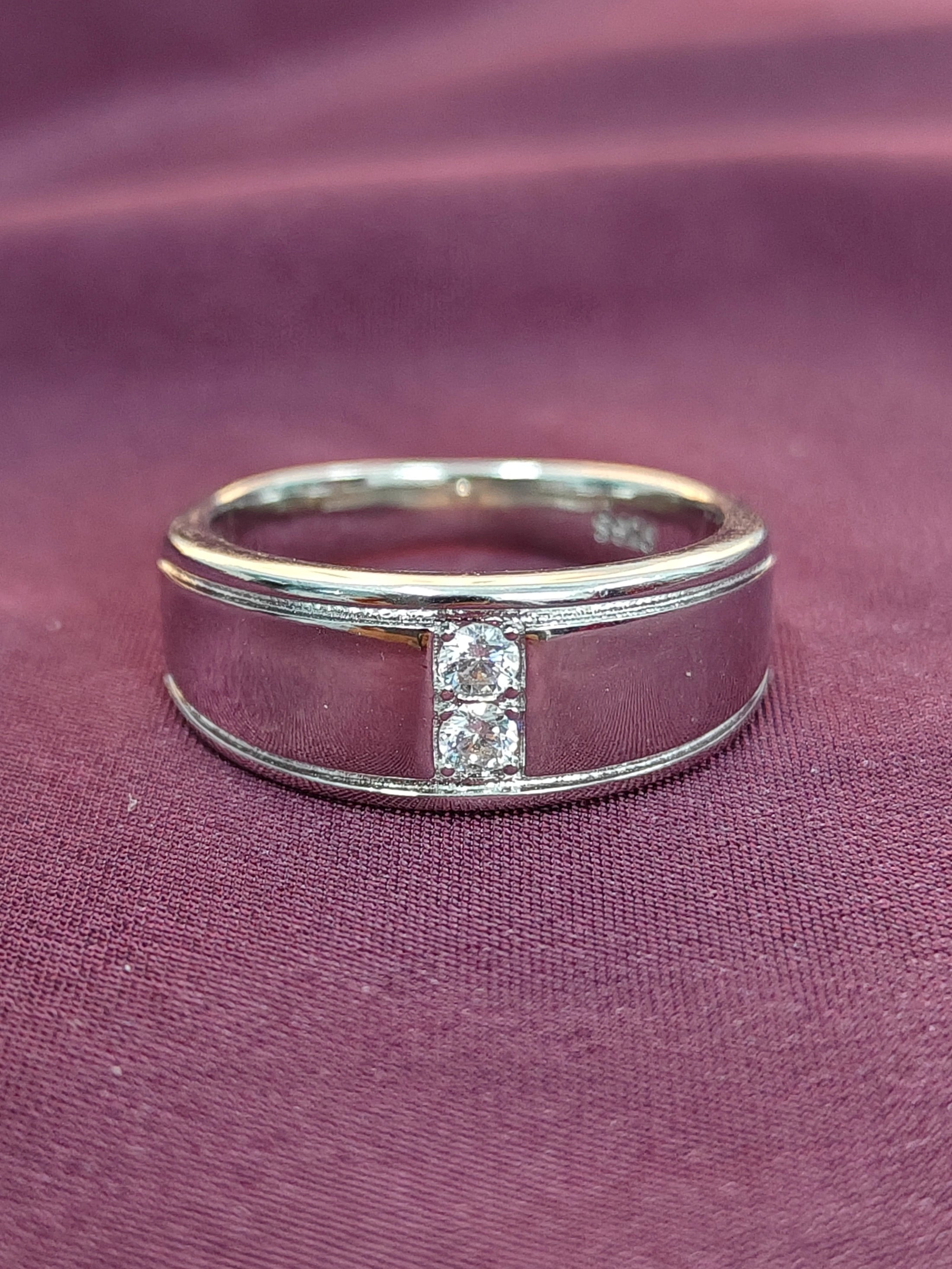 Silver ring with diamonds on a purple fabric background